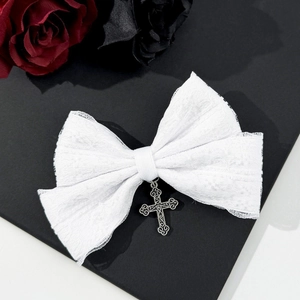 Detailed shot of white lace bow hair clip featuring a vintage metallic cross pendant