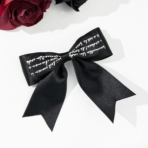 Vintage black satin bow hair clip with white script lettering for elegant hair styling