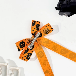 Detail of Halloween bow hair clip with pumpkin and bat prints on orange ribbon