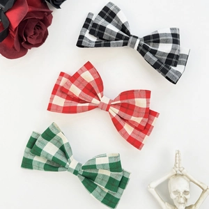 Three plaid bow hair clips in black, red, and green with a retro decorative background