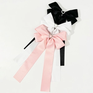 Vue détaillée de grandes barrettes à nœud en satin noir, blanc et rose avec cristaux cœur
