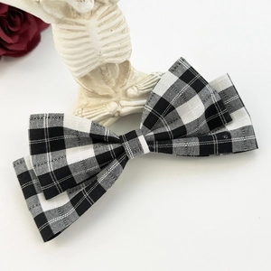 Classic black and white checkered bow hair clip on a white background with gothic props