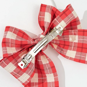 Close-up of red plaid bow hair clip showing the silver metal spring clip and texture