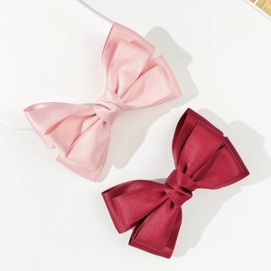 Dettaglio di fermagli per capelli a doppio fiocco in raso, colori rosa e bordeaux