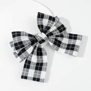 Close-up of black and white plaid bow hair clip with detailed woven fabric texture