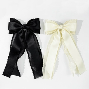 Detail view of elegant black and ivory satin bow hair clips with delicate lace edges