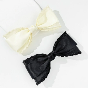 Elegant set of black and creamy white bow hair clips with scalloped edges and silky texture