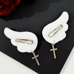 Detail of gothic angel wing hair clips with plush white fabric and silver cross charms