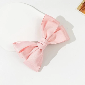 Dettaglio del fermaglio per capelli con fiocco in raso rosa su un supporto bianco