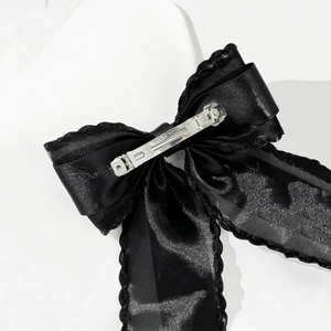 Detail of black satin bow hair clip featuring a secure silver metal spring clasp and lace trim