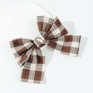 Japanese brown plaid bow hair clip with spring fastener on a white minimalist background