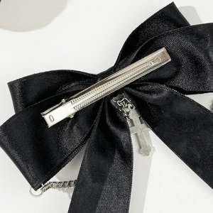 Detail of black satin bow hair clip with silver cross pendant and punk metal chains