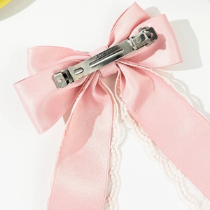 Macro detail of silver metal spring clip and pink satin bow with white lace trim