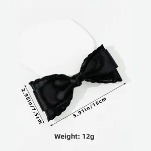 Detail of elegant black satin bow hair clip with lace trim and precise 15cm size markers