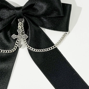 Macro detail of gothic black satin bow hair clip with silver cross pendant and chain
