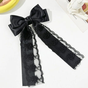 Detail view of black satin bow hair clip featuring delicate lace ribbon and floral embroidery