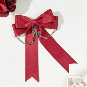 Detail of gothic burgundy satin bow hair clip with silver metal chain and cross pendant