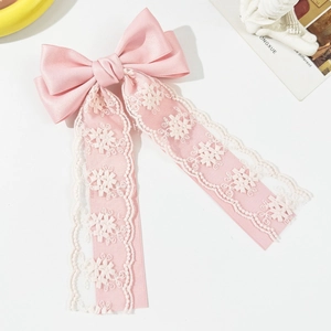 Close-up of pink ribbon hair clip with white floral lace embroidery and silky bow detail