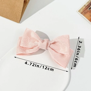 Detail view of pink bow hair clip showing fabric texture and 12cm size measurements