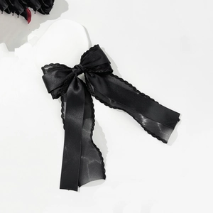 Elegant black satin hair clip with delicate lace trim and long ribbons on white background