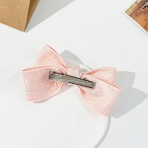 Close-up of a pink jacquard ribbon hair clip with a silver metal duckbill clamp