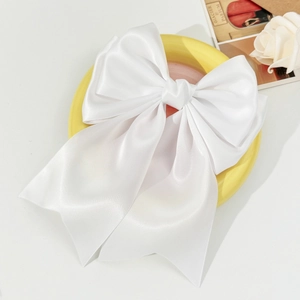 Detail of white satin oversized bow hair clip with a smooth glossy silk finish