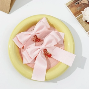 Gros plan de barrettes à nœuds roses avec pendentifs en cœur sur une assiette en céramique