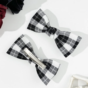 Detailed view of two gingham bow hair clips with silver metal duckbill back clips