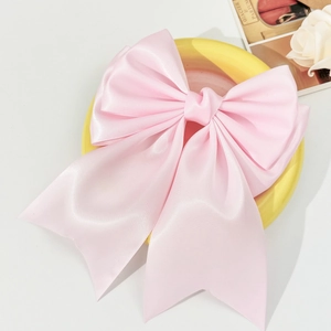 Detail of elegant pink satin bow hair clip with double-layer design on a tray