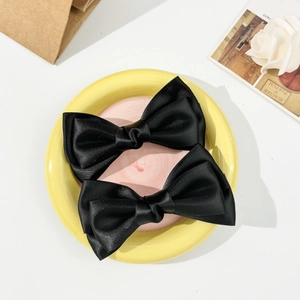 Détail de deux nœuds à cheveux en satin noir posés sur une assiette en céramique jaune