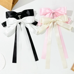 Detailed view of large satin bow hair clips with long ribbons in four elegant colors