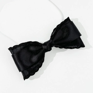 Detailed close-up of double-layered black satin ribbon hair clip with elegant scalloped edges