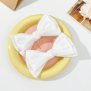 Gros plan de barrettes à cheveux en satin blanc avec nœud dans un plat en céramique