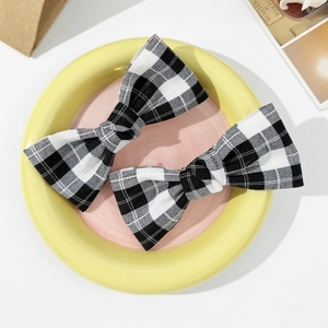 Close-up of vintage black and white plaid bow hair clips with soft fabric texture
