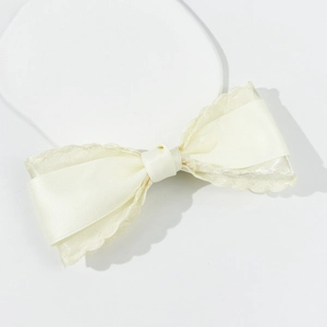Close-up of elegant cream-colored bow hair clip with satin fabric and lace detail