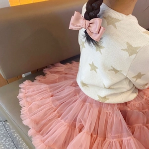 Detail of pink satin bow hair clip on a girl wearing a white knit sweater and pink tutu