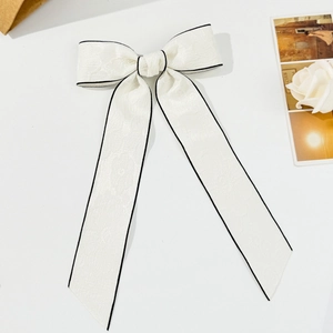 Dettaglio del fermaglio per capelli a fiocco bianco con bordi neri e trama jacquard