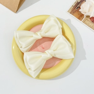 Détail de barrettes à nœuds en satin de soie crème dans un plateau décoratif chic