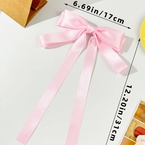 Detail view of a pink satin bow hair clip with long ribbons showing 17cm by 31cm dimensions
