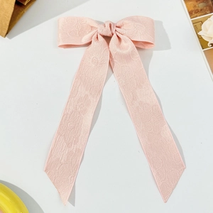 Dettaglio del fermaglio per capelli con fiocco in jacquard rosa e nastri lunghi