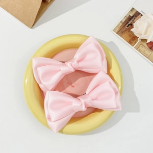 Vue détaillée de deux pinces à cheveux en satin rose clair sur une assiette décorative