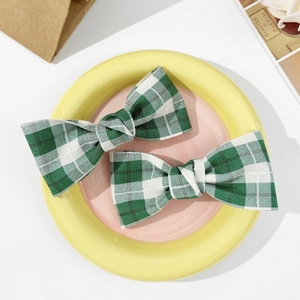 Close-up of dual green plaid bow hair clips made of vintage fabric on a decorative plate