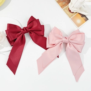Elegant satin bow hair clips in wine red and soft pink with long ribbons and smooth texture