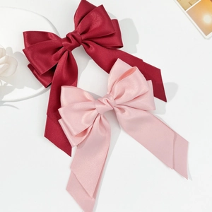 Detail of elegant satin bow hair clips in wine red and light pink with long ribbons
