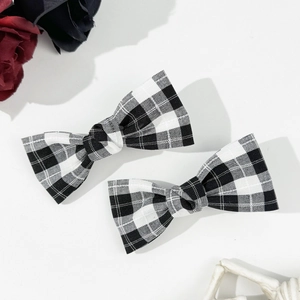 Close-up of black and white plaid bow hair clips with vintage gothic rose decorations