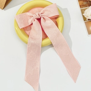 Dettaglio del fermaglio per capelli rosa con trama jacquard rosa e lunghi nastri