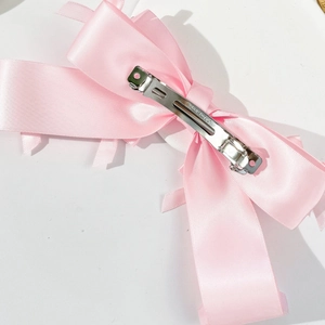 Close-up of pink satin bow hair clip featuring a durable silver metal spring fastener
