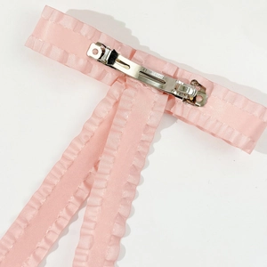 Detail of pink satin bow hair clip featuring a secure silver metal spring clip fastener