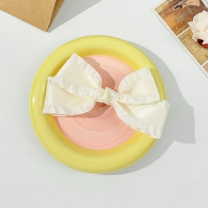 Detailed macro view of the ruffled cream satin bow hair clip with glossy silk texture
