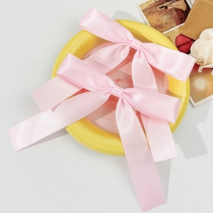 Lot de deux nœuds à cheveux en satin rose ballet sur un plateau décoratif jaune